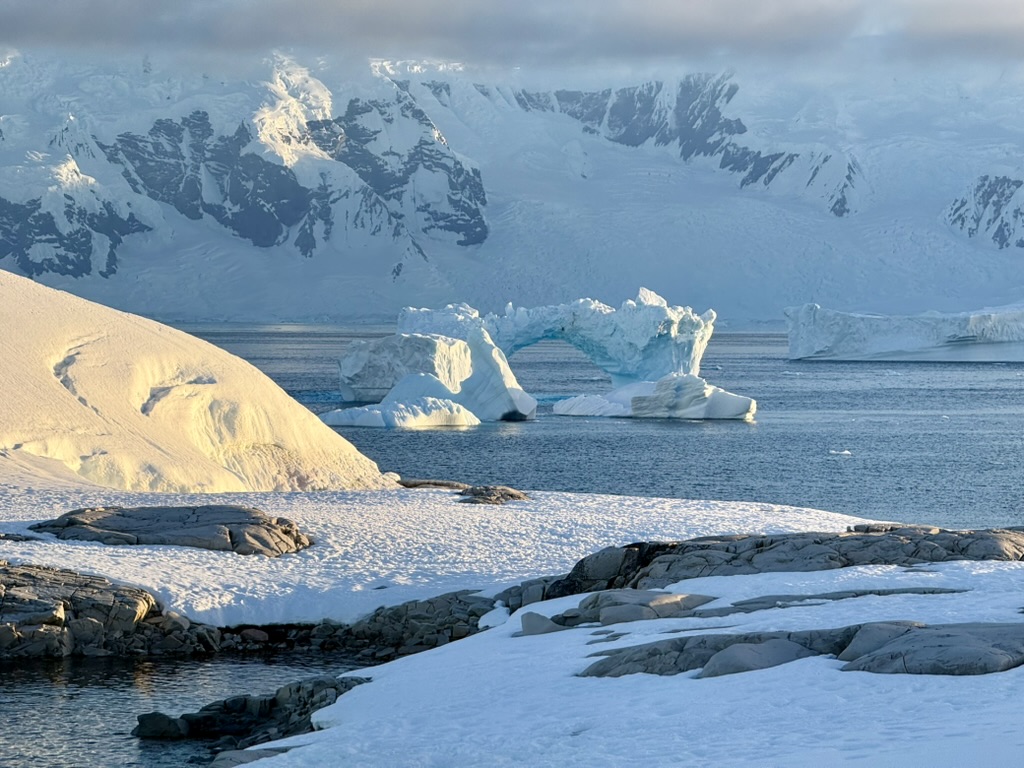 Warm sunlight falling across ice and an Antarctic shoreline