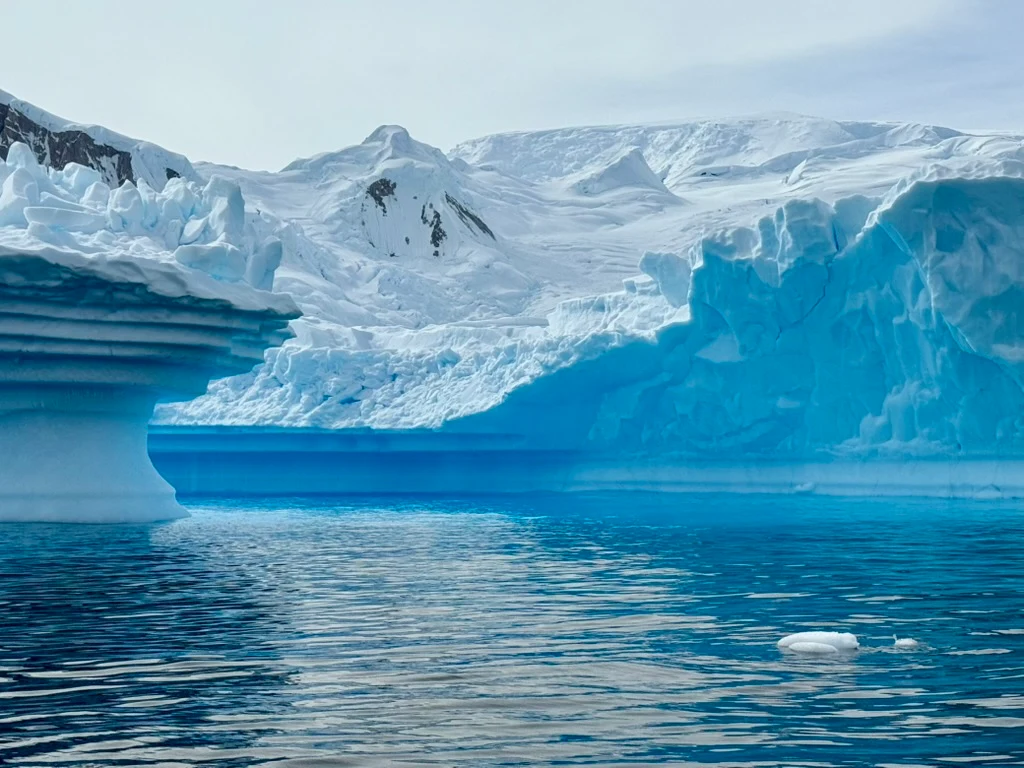 Brilliant blue glacier and iceberg reflected in Antarctic water