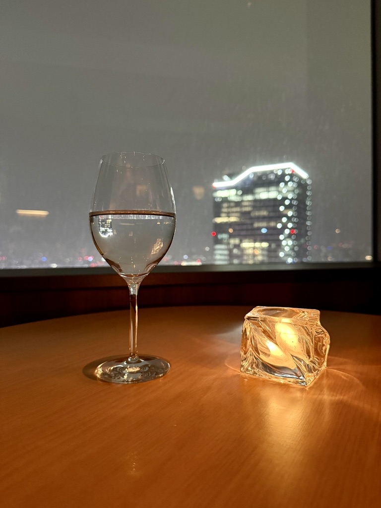 A wineglass and candle beside a city window